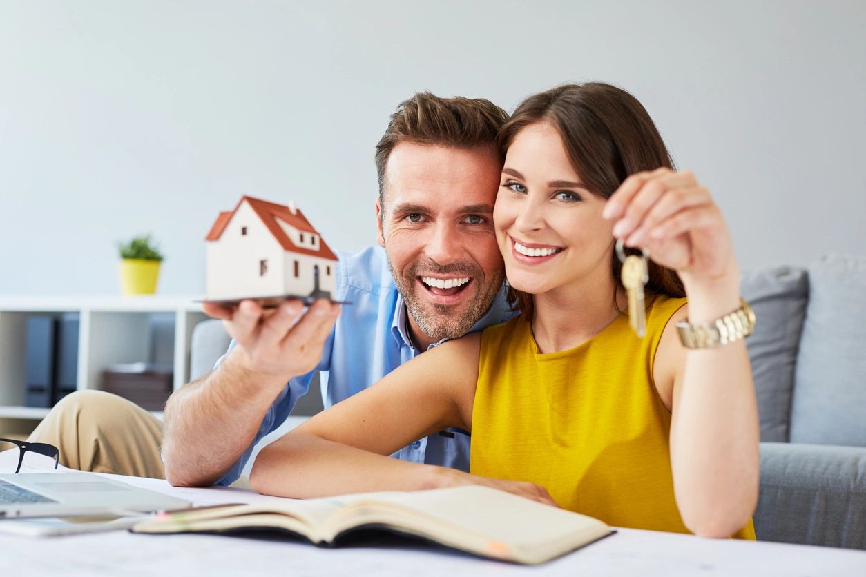 A man and woman holding keys to their new home.